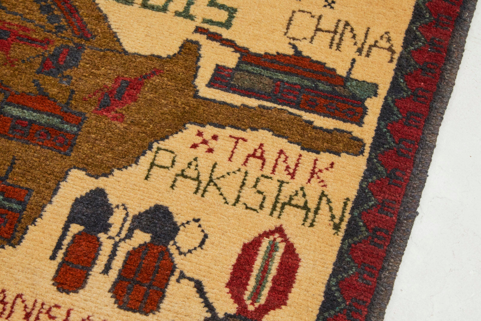 Hand woven Afghan war rug with map images, tanks, weapons and the words "Pakistan," "2015," "Made in Afghanistan" with cream background and red, brown and blue images - Available from King Kennedy Rugs Los Angeles