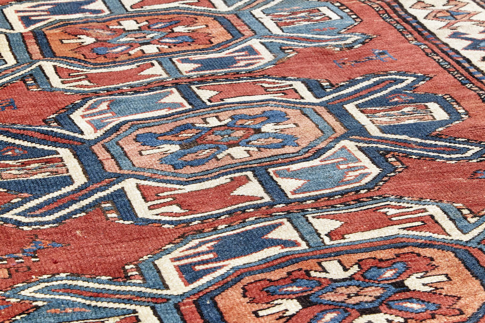 Antique hand woven Karabaugh Persian Rug with red base and multiple medallions in pink, cream and blue with white border and beautiful shapes and symbols woven throughout. A perfect addition to a bedroom, dining room or kitchen. Available from King Kennedy Rugs Los Angeles
