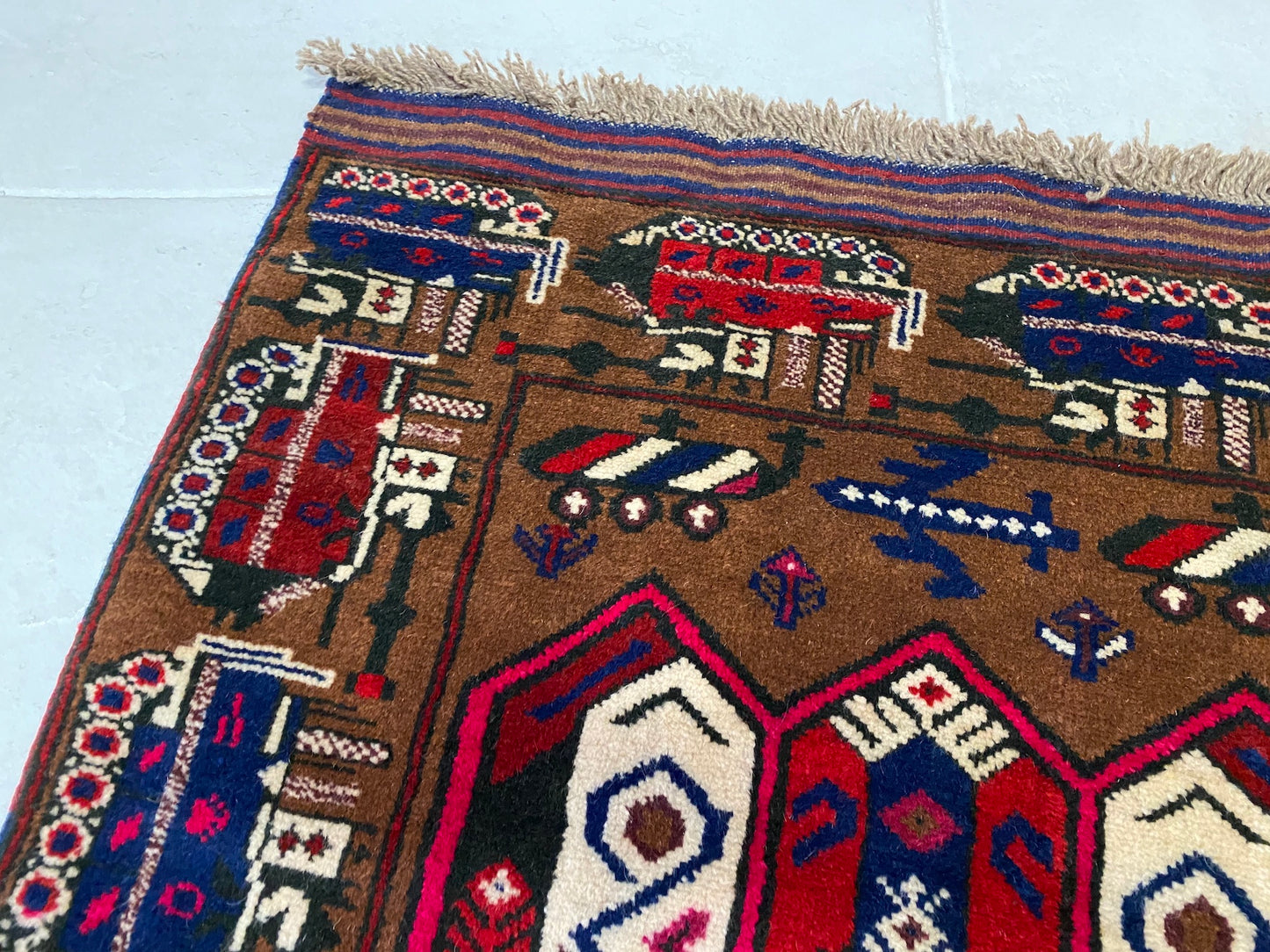 Hand woven Afghan War Rug with tan base and vibrant blue, red and cream tanks and symbols throughout - Available from King Kennedy Rugs Los Angeles