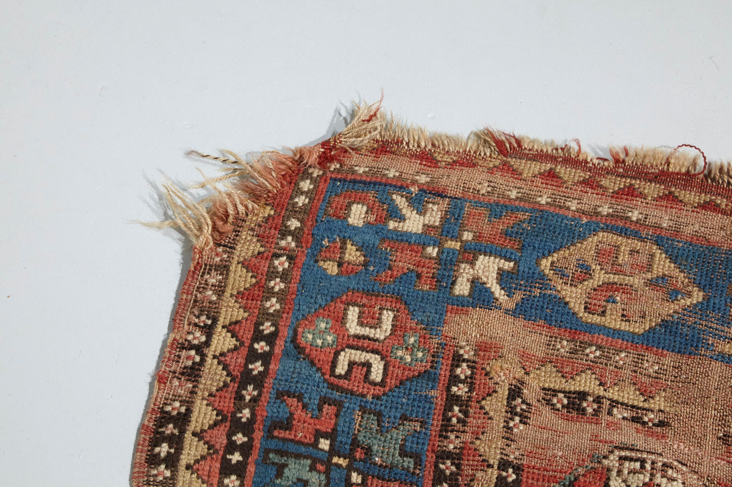 Corner detail of beautifully worn antique Kazak Persian Rug with red, blue and cream colors - Available from King Kennedy Rugs Los Angeles