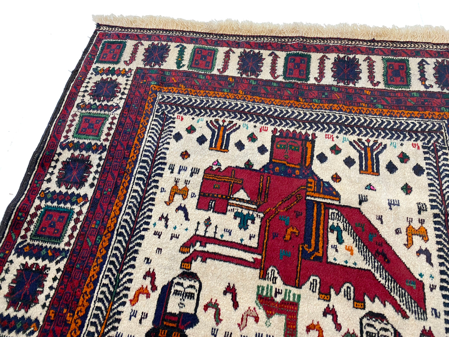Detail of rider on Afghan pictorial rug with cream base and three figures in blue cloaks across the middle, figures with crowns on horses at the top and bottom of rug woven in deep blue and reds