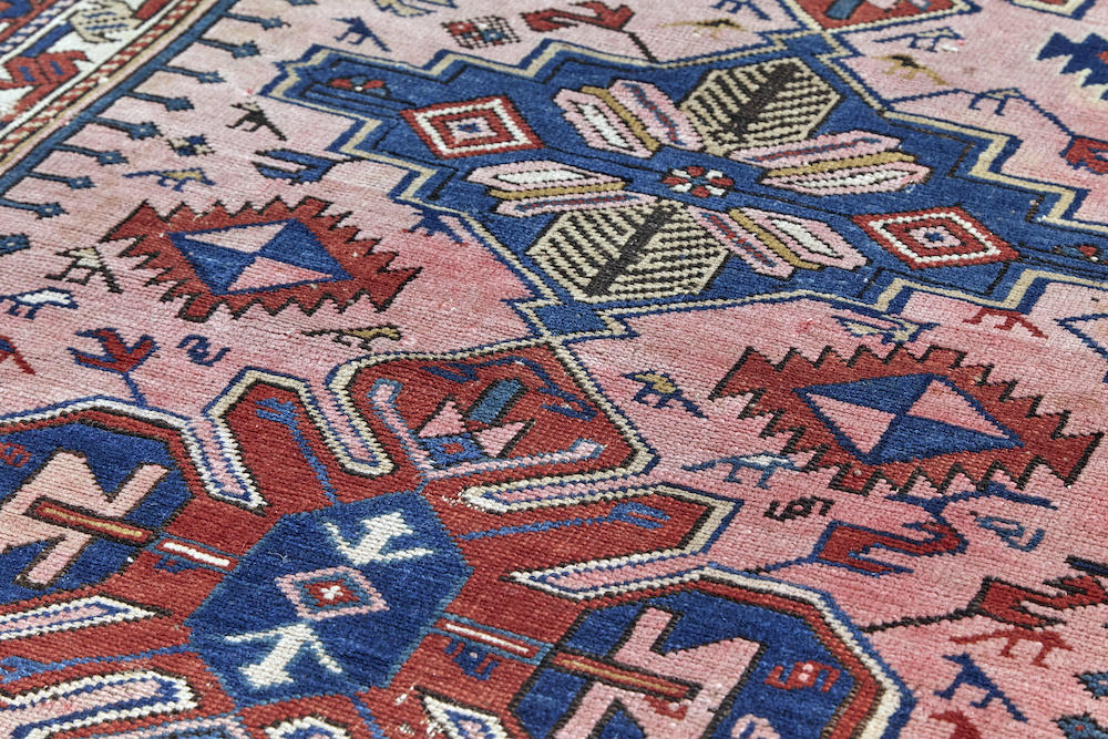 Antique Persian Caucasian rug in pale pink with deep red and blue designs throughout. Perfect for a bedroom, study, kitchen or living room. Available from King Kennedy Rugs Los Angeles