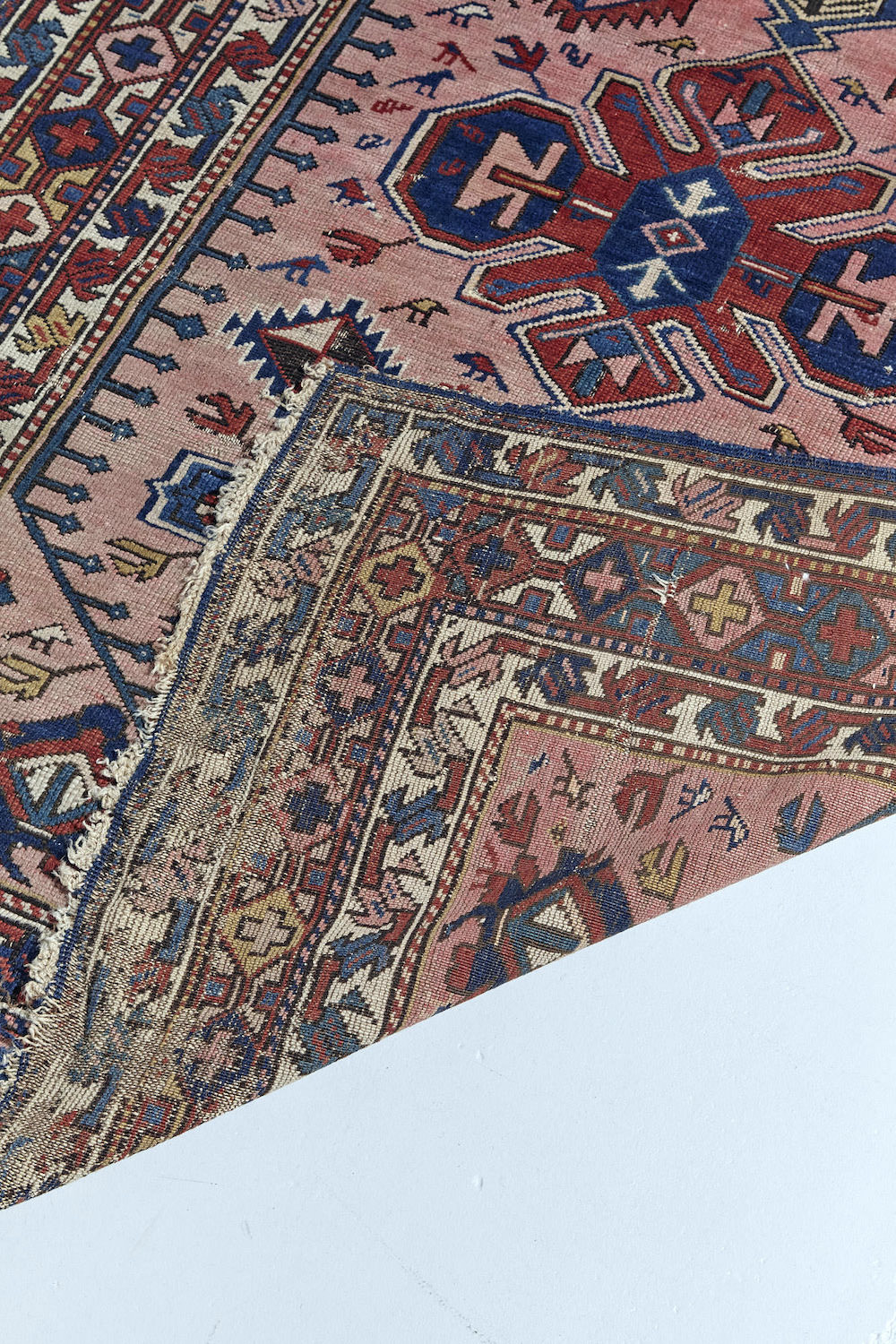 Antique Persian Caucasian rug in pale pink with deep red and blue designs throughout. Perfect for a bedroom, study, kitchen or living room. Available from King Kennedy Rugs Los Angeles