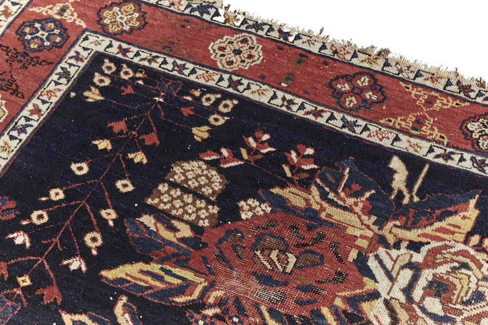 Antique hand woven Caucasian rug, depicting three clusters of roses. Beautiful dark blue base with red and cream roses. Red border with cream, gold and brown shapes. Perfect for a bedroom or study. Available from King Kennedy Rugs Los Angeles