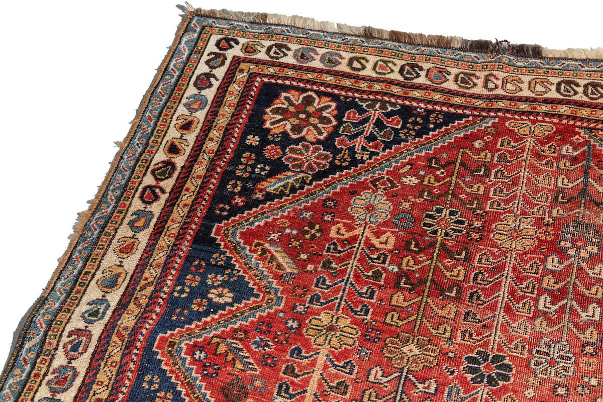 Border detail of Kashkai antique Persian rug with red base, cream border and deep blue details. Plants and flowers woven throughout. Perfect for a bedroom or study.Available from King Kennedy Rugs Los Angeles