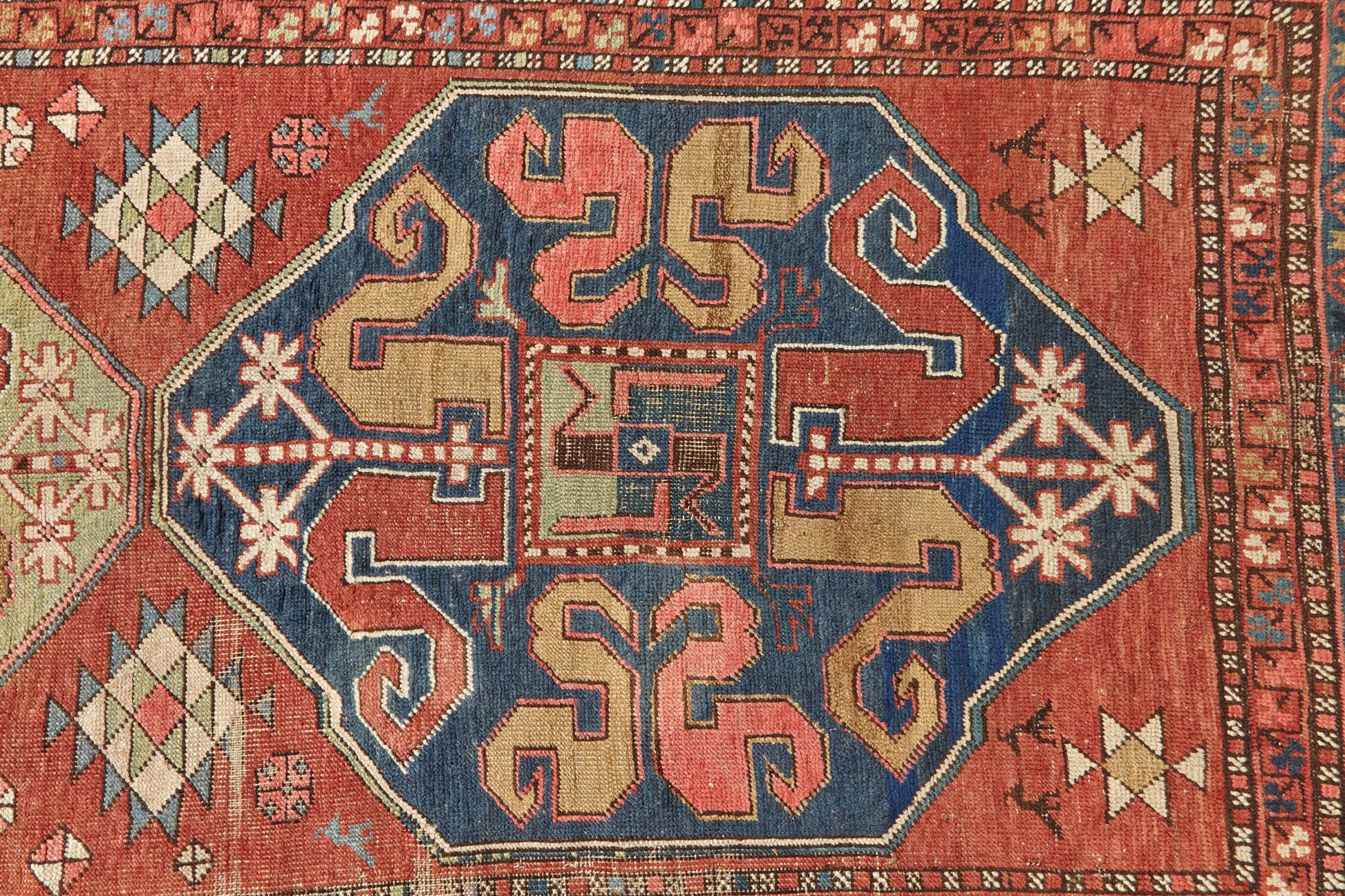 Kazak Cloudband antique Persian rug with rich pink base and two large medallion designs in the center, one pale green, one blue with pink, red, gold, cream and blue designs intricately hand woven throughout. A beautiful piece for a bedroom, hallway, dining room or study - Available from King Kennedy Rugs Los Angeles