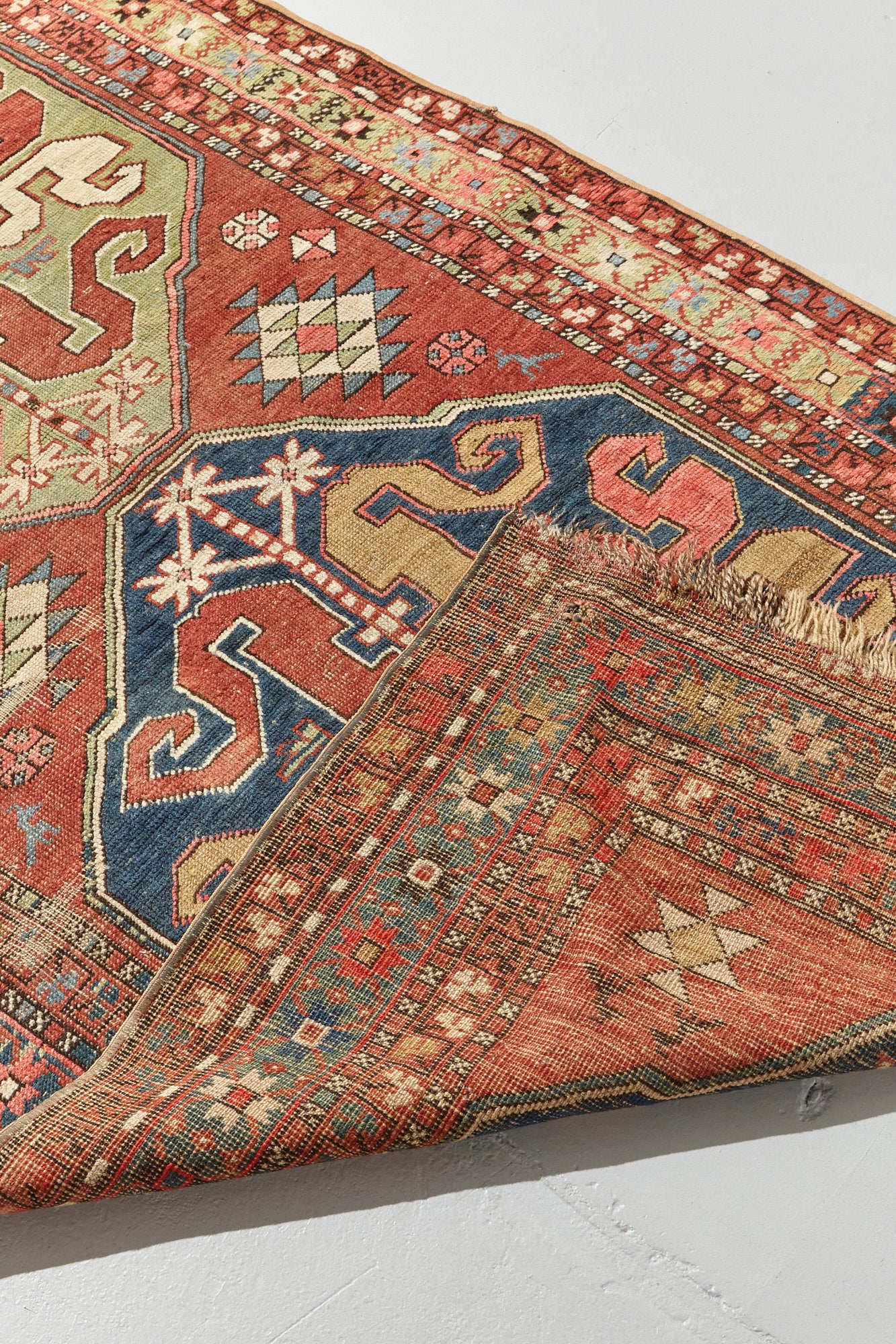 Front and back of Kazak Cloudband antique Persian rug with rich pink base and two large medallion designs in the center, one pale green, one blue with pink, red, gold, cream and blue designs intricately hand woven throughout. A beautiful piece for a bedroom, hallway, dining room or study - Available from King Kennedy Rugs Los Angeles