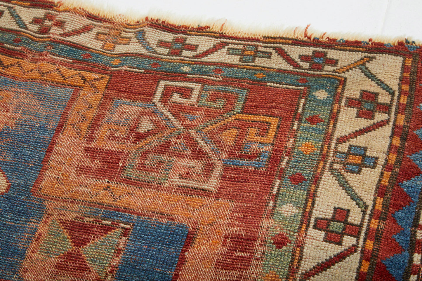 Detail of corner border of antique Kazak Persian Rug with red, tan, blue and cream colors - Available from King Kennedy Rugs Los Angeles