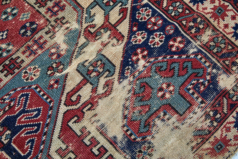 Close-up of wear on intricate handwoven Kazak red, cream, dark blue and green Persian area rug - available from King Kennedy Rugs Los Angeles