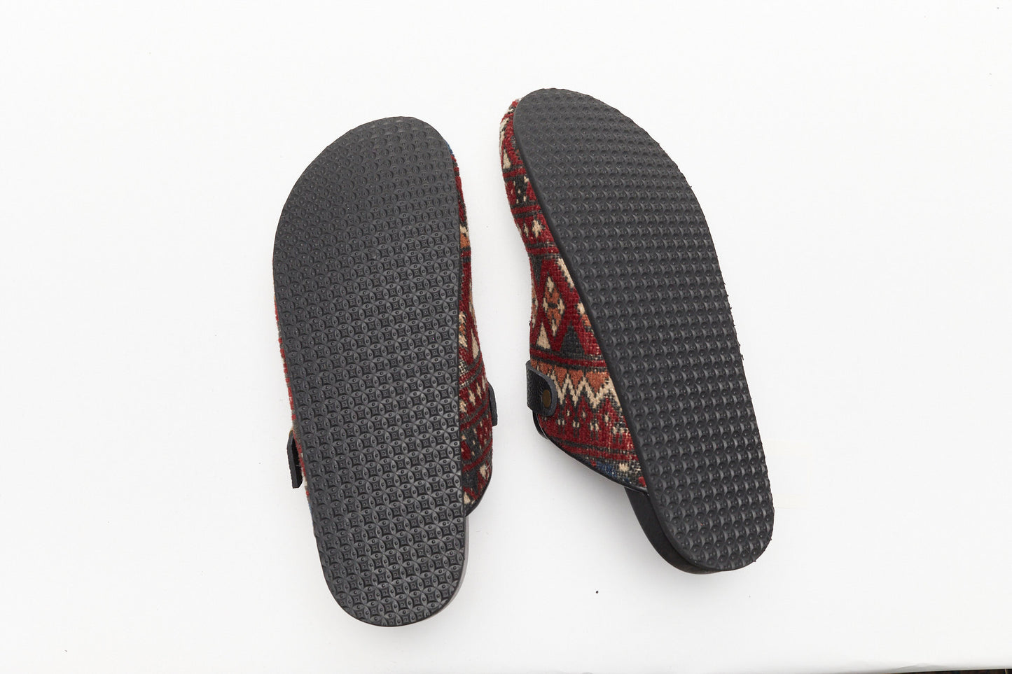 Rubber soles of rug mules. King Kennedy Rug Mules are one-of-a-kind and made of 100 year old antique Persian rug fragments with soft lambskin footbed and comfortable rubber sole. This pair is made of an antique Persian rug with vibrant deep red, cream, tan and dark grey patterns throughout.