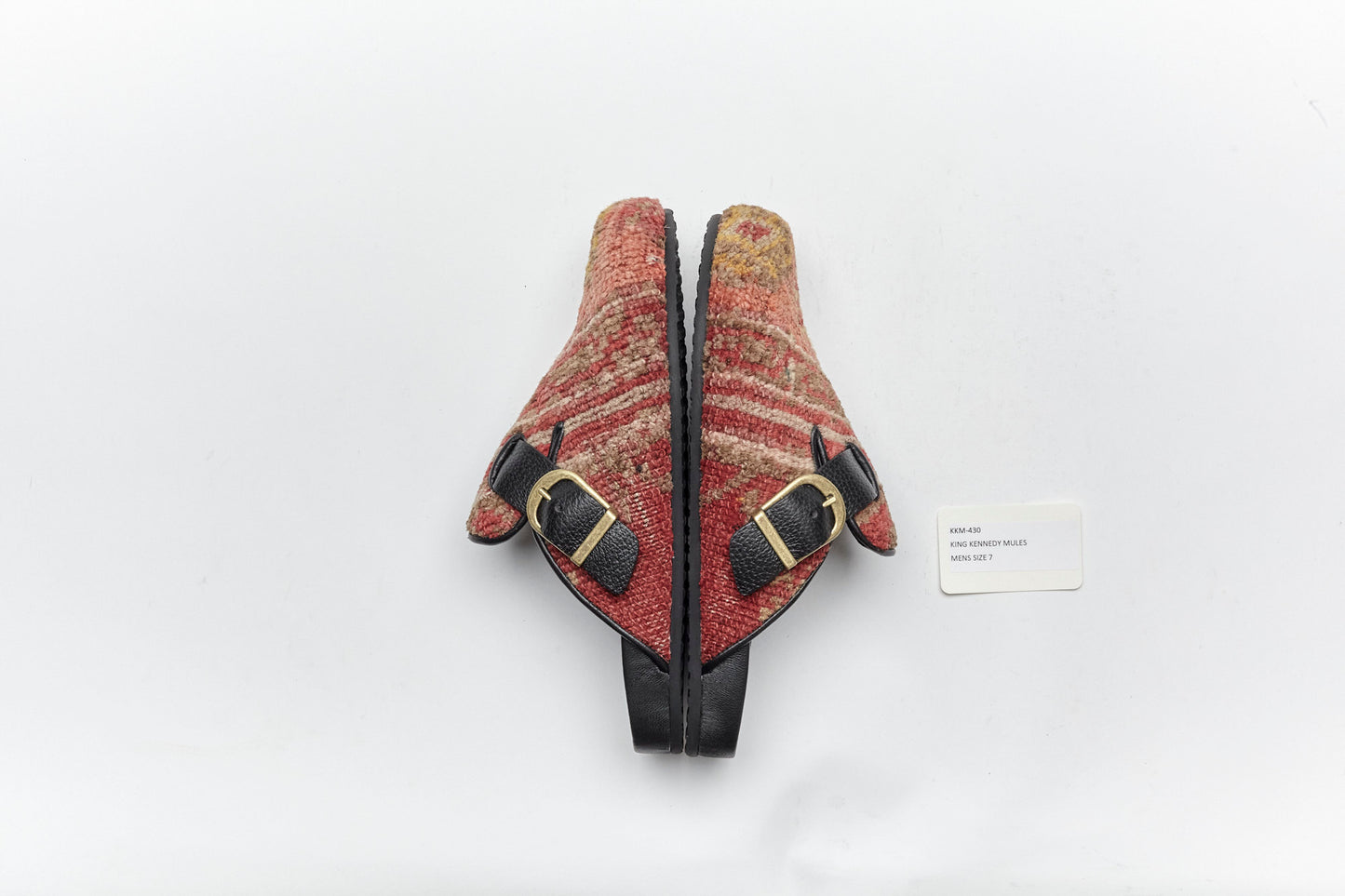 Side view with brass buckles of King Kennedy Rug Mules.  King Kennedy Rug Mules are one-of-a-kind and made of 100 year old antique Persian rug fragments with soft lambskin footbed and comfortable rubber sole. This pair is made of an antique hand knotted Persian rug with pink, red and yellow tones. 