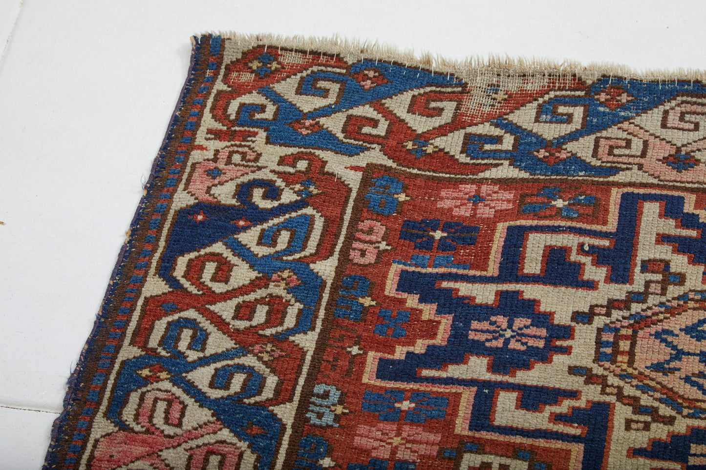 Detail of antique hand woven Persian rug with cream and blue star and flower shapes on red base - Available from King Kennedy Rugs Los Angeles