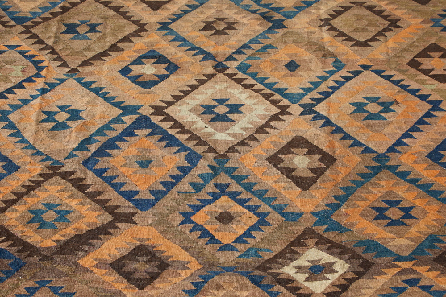Maimana Turkish Kilim area rug with tan, beige and brown earthy tones, along with blue, cream and peach geometric patterns. Hand woven large area rug - Available from King Kennedy Rugs Los Angeles