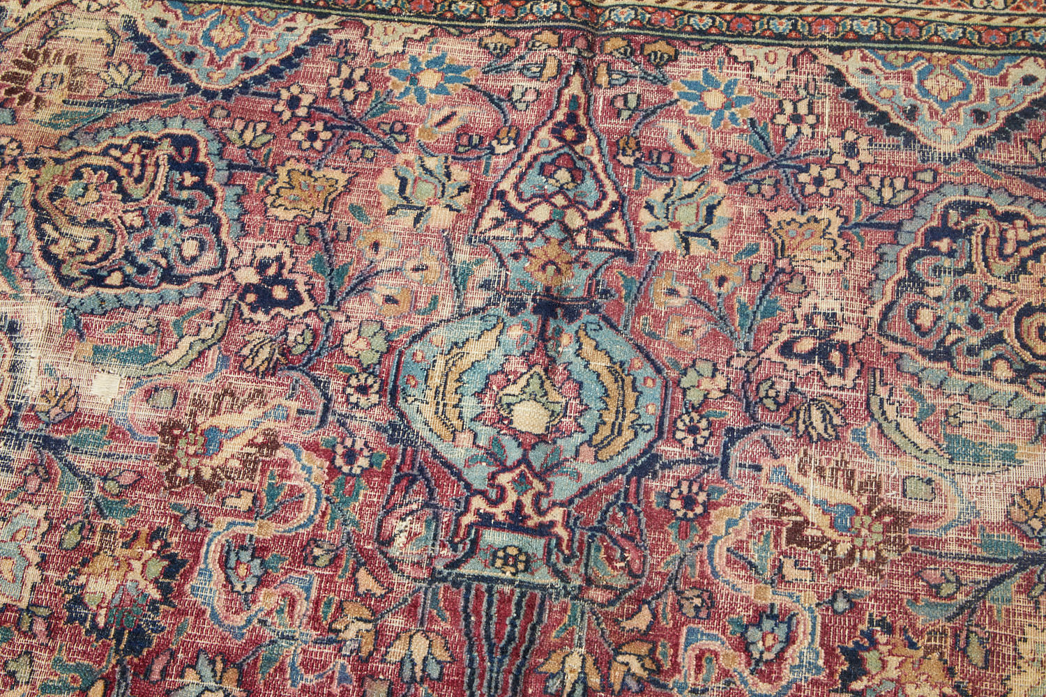 Hand woven antique room-sized Meshed Persian Rug with burgundy purple red base and blue, cream and gold intricately woven patterns of flowers and vines with large medallion in center - Available from King Kennedy Rugs Los Angeles