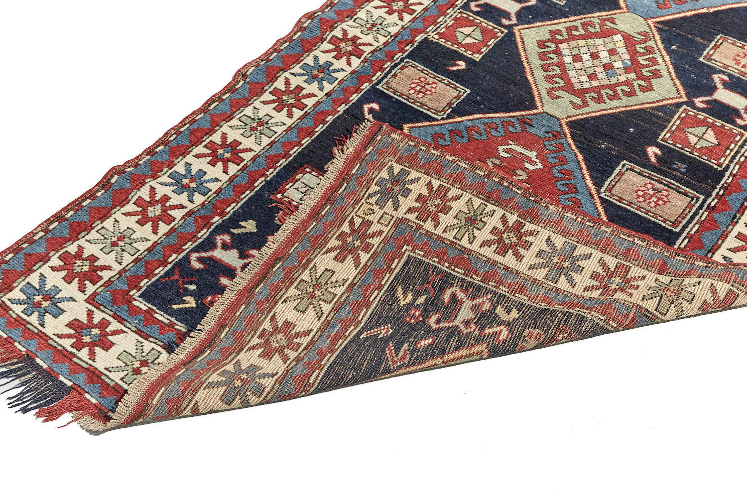 Front and back of Antique hand woven Kazak Persian rug with dark blue base, blue and pale green diamonds across center with a cream and red border, featuring red, pale green and blue star-like shapes. Perfect for bedroom, living room dining room or kitchen. Available from King Kennedy Rugs Los Angeles.