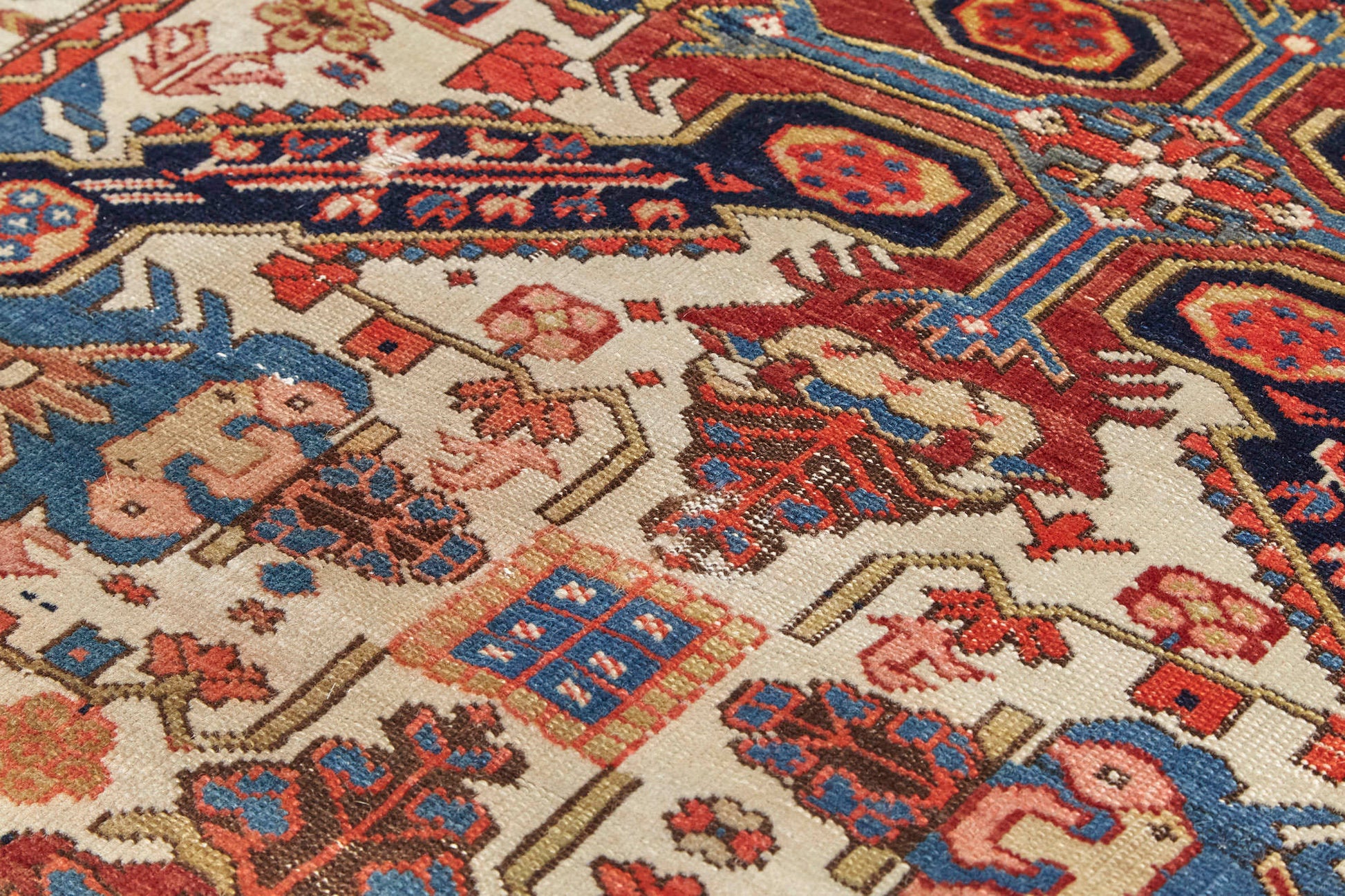 Detail of weave on intricately woven Zeychour Persian rug. Vibrant red and deep blue medallions with floral motifs throughout and border with red flowers and blue and white wave pattern. Available from King Kennedy Rugs Los Angeles