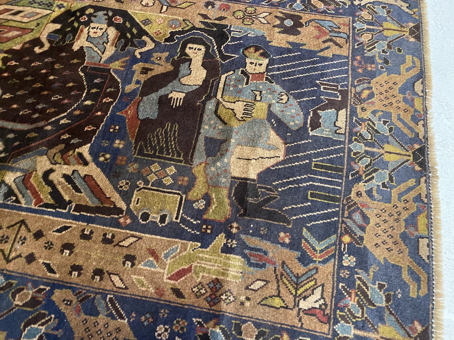 Detailed hand woven Afghan Pictorial Rug depicting figures around a fire near a caravan, along with deep blue hues with beige, black and pale green details of plants and animals. Perfect for a bedroom, living room, studio or study.Available from King Kennedy Rugs Los Angeles