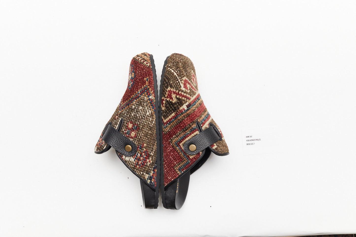 Side view of rug mules.  King Kennedy Rug Mules are one-of-a-kind and made of 100 year old antique Persian rug fragments with soft lambskin footbed and rubber sole. This pair is made of an antique Persian rug with a taupe, tan base with red and cream patterns. Made in Los Angeles.
