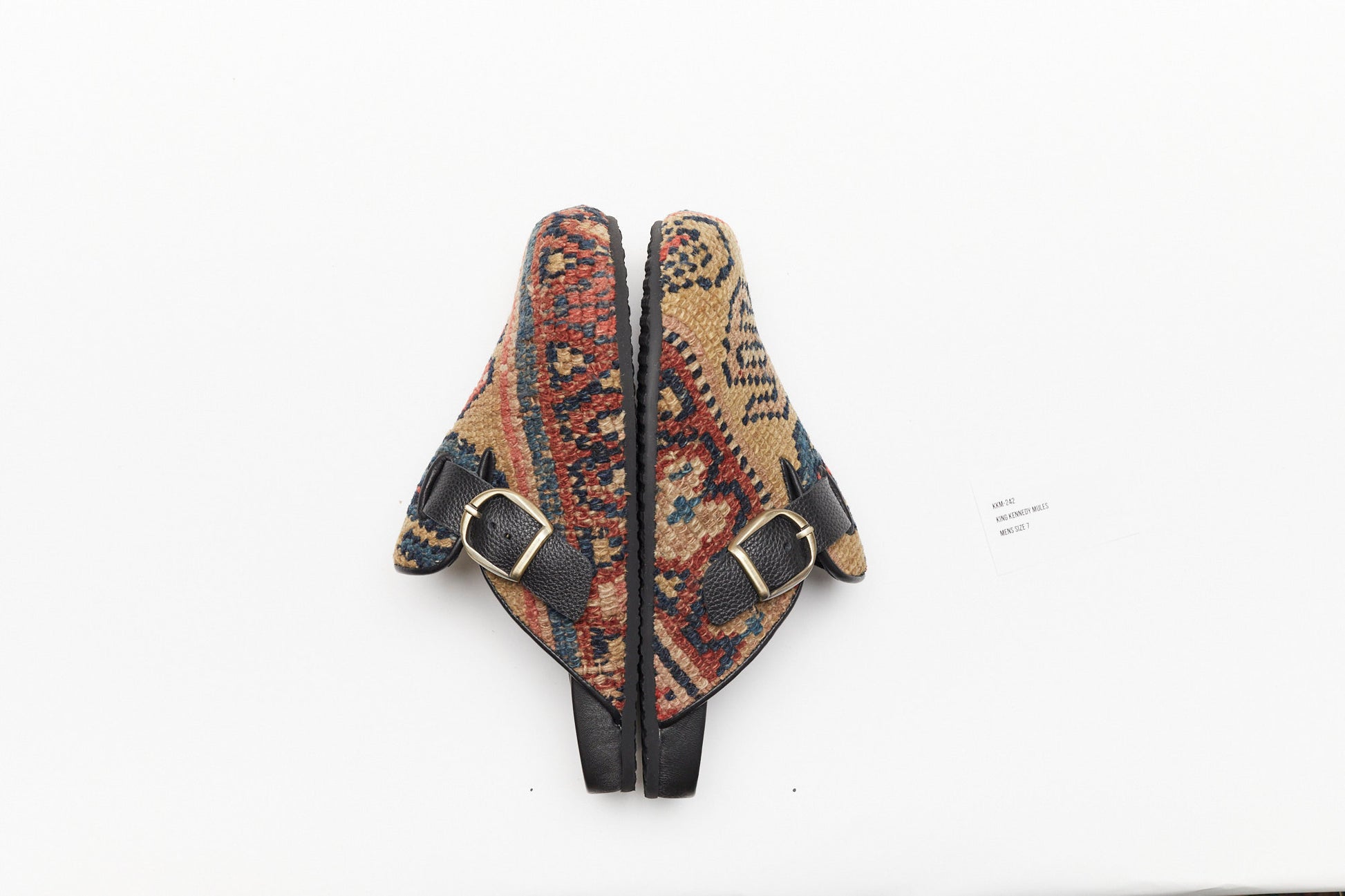 Buckle side view of rug mules. Side view of rug mules. This pair of King Kennedy Rug Mules are one-of-a-kind and made of 100 year old antique Persian rug fragments with soft lambskin footbed and rubber sole.  This pair is made of a taupe, beige rug with pale red and blue designs.  